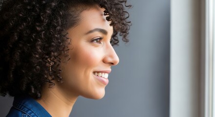 Smiling young african female with curly hair looking out of window