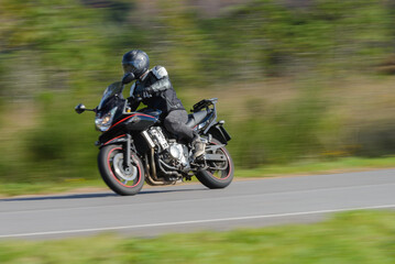 biker on a sport motorcycle rides fast while leaning on a turn on a winding road, motion blur highlighting the dynamic action