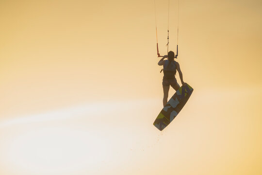 Woman kitesurfing at sunset in Mayapo, La Guajira