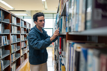 Young student man finding book on the bookshelf in college library. learning or information in university.