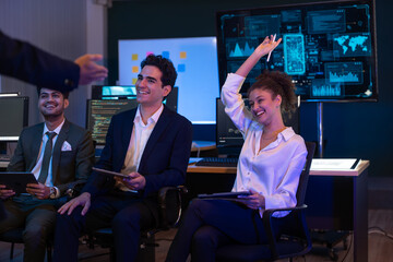 Group of professionals businesswoman and businessman in formal attire discussing ideas on innovative technology development project with tablets and laptops in dark modern office