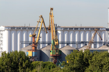 Fototapeta premium Industrial cranes working at storage facility near urban area