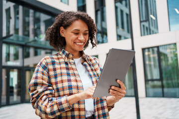 A Happy and Smiling Woman Engaged with Her Tablet in a Dynamic Urban Environment Setting