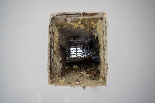 Closeup of neglected old ventilation hole in the wall of a house, covered with dust and cobwebs