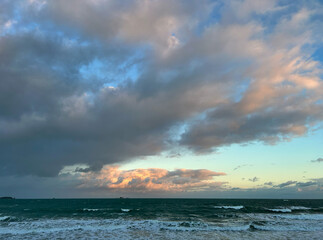 Sunset light over stormy Atlantic waves and wooden breakwaters, Brittany coast