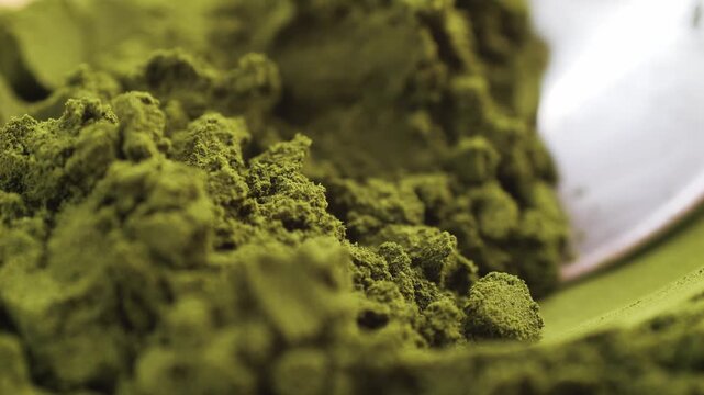 Green chlorella algae powder on a wooden spoon, top view. Healthy nutritional supplement.