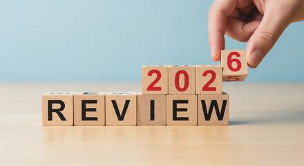 Hand placing block to complete year 2026 review concept