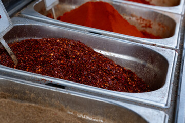 Close-up of red chili pepper flakes (Capsicum annuum) in metal container at local market in Tel Aviv, Israel — vibrant culinary spice and food texture background