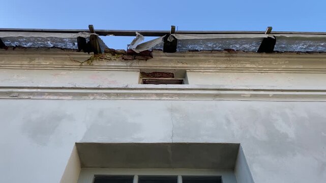 Close-up of new house wall showing construction defect, cracked plaster and damaged roof detail
