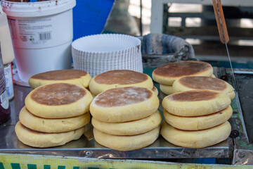 Several stacks of freshly baked gorditas de nata, a popular traditional Mexican sweet cream flatbread pastry, displayed on a street food stall in Guadalajara, Mexico
