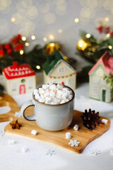 Cozy mug of hot chocolate with marshmallows and winter village decoration
