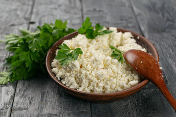 Fresh Cottage Cheese in Rustic Bowl with Parsley and Wooden Spoon on Wooden Table