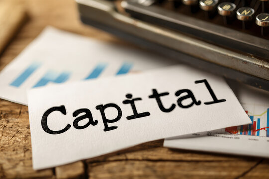 Typed word capital on paper with financial charts, symbolizing investment, business, and economic planning.