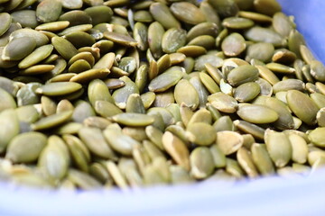 A close-up shot of a bowl filled with pumpkin seeds