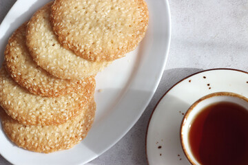 Sesame cookies in a plate on the table, next to a cup of black tea
