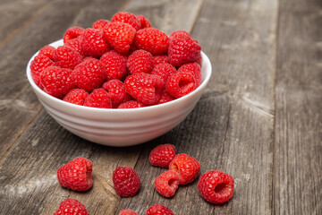 Sweet summer raspberries on a wooden plank background, focus on the berries.

