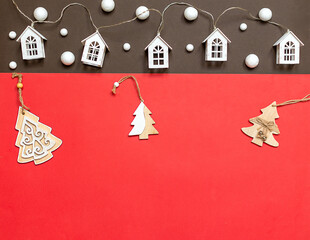 Christmas background with Christmas tree decorations and a garland with houses, space for a copy. Beautiful holiday Christmas card, red and brown background, space for copy, text and advertising