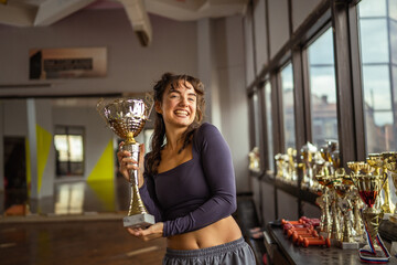 Young woman celebrating success holding gold trophy
