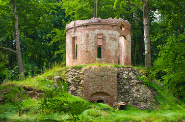 Ancient ruin stands amidst lush green forest landscape, Pokoj, Poland