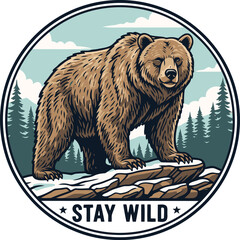 Grizzly bear standing on rocks in a snowy forest with the words stay wild