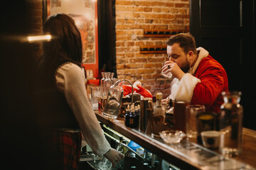 Tired santa claus drinking at a festive bar