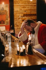 Stressed santa claus holding head at bar counter
