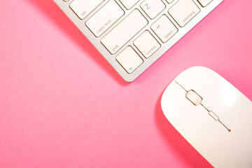 Computer keyboard and mouse on pink background. Top view with copy space