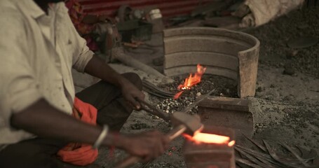Cinematic shot of Indian blacksmiths forging tools like hoe, sickle, and  spade in a workshop