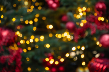 Blurred Christmas tree with red balls and lights garland. Abstract pattern. Defocused background. Xmas holiday spirit.