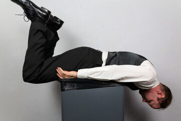 Washed Up Businessman Lying Atop a Garbage Can. Concept of Being Sacked or Fired.