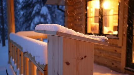 Cozy log cabin porch railing covered in fresh snow at dusk with warm light glowing from window and falling snowflakes creating a magical winter atmosphere perfect for Podium - Powered by Adobe