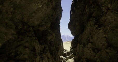 Natural rock formations frame a beautiful view of distant sand dunes under a clear blue sky. The rugged texture contrasts with the soft dunes visible in the distance.