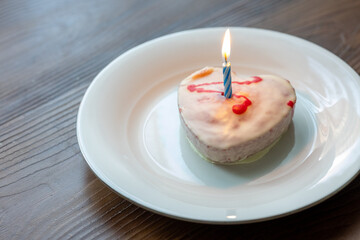 Close-Up of Heart-Shaped Strawberry Birthday Cake with a Burning Candle on a White Plate
