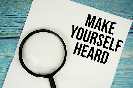 Make Yourself Heard text written on notepad with magnifying glass flat lay on wooden background