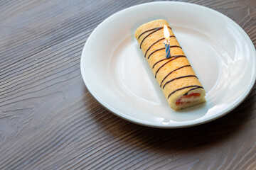 Close-Up of Mini Strawberry Roll Cake and Birthday Cake with a Burning Candle on a White Plate
