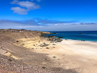 Beautiful coastal landscape view of Playa Chorrillos in northern Chile. Turquoise water, white golden sand, and sandy rock formations under a bright blue sky. 