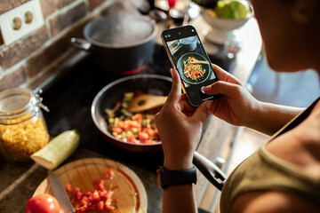 Woman photographing her meal while its cooking