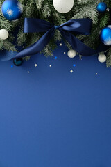 Festive pine arrangement with navy ribbon, glittery baubles, and star confetti on blue. Rich Merry...