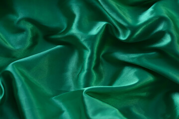 Fototapeta premium A closeup minimalist textured pattern. Green satin fabric texture luxurious shiny. Background with pattern soft waves blur beautiful.