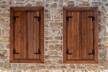 Stilvolle Fassade eines Hauses mit eine Fassade aus Natursteinen und hölzernen Fensterläden