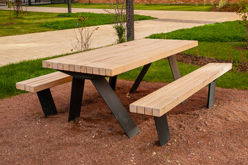 outdoor picnic bench table for 6 people from Douglas fir. wooden picnic table with black metal legs sits on gravel in a well-maintained garden