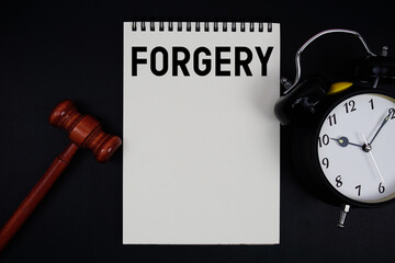 Forgery text written on notepad with gavel and alarm clock on black background
