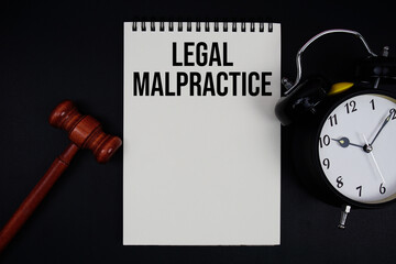 Legal Malpractice text written on notepad with gavel and alarm clock on black background