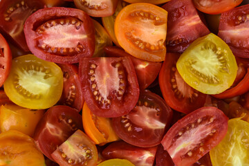 Group of ripe fresh different tomatoes, sliced in half. Food background. Cut colorful juicy  tomatoes close up. 