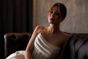 Elegant bride posing in minimalist wedding gown in modern interior with soft natural light