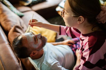 Daughter applying face mask to father at home
