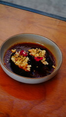 Platillo gourmet con chiles rellenos bañados en salsa roja, con camarón y decorados con pétalos comestibles.