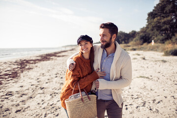 Young couple walking on beach in autumn