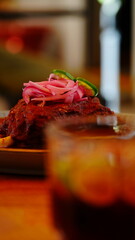 Platillo tradicional mexicano bañado en salsa roja, decorado con cebolla morada encurtida y rodajas de chile verde.