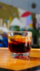 vaso corto con bebida oscura y rodajas de limón. Fondo tropical y ambiente relajado.